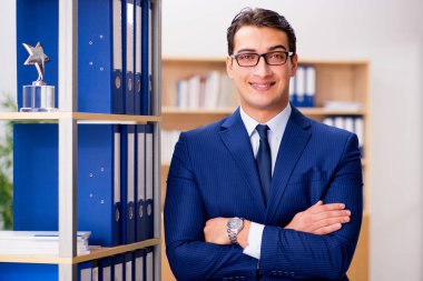 Yakışıklı işadamı raf yanında ayakta