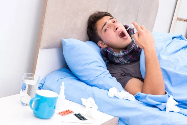 Grip olmuş hasta adam yatakta yatıyor.