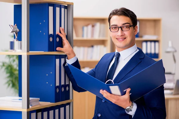 Stilig affärsman står bredvid hyllan — Stockfoto