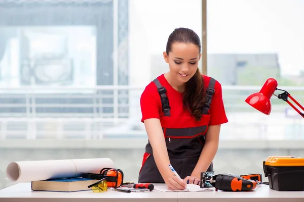 Young woman in coveralls doing repairs — Stock Photo, Image