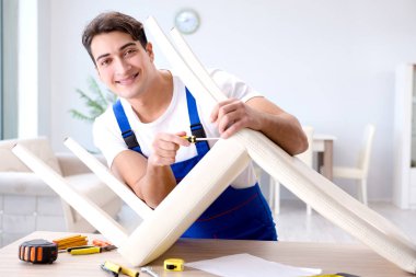 Odadaki sandalyeyi tamir eden adam.