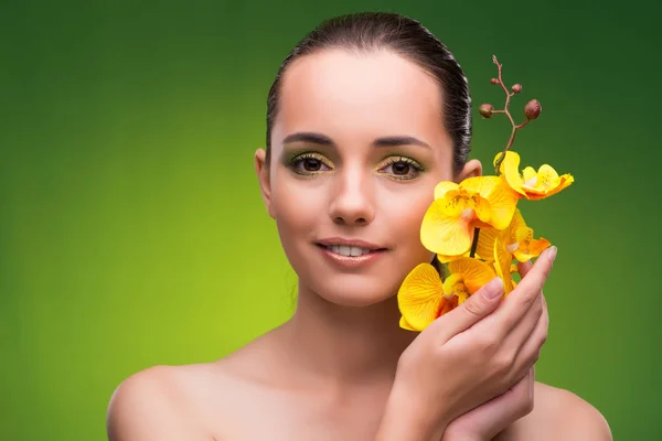 Vacker kvinna med gul orkidé blomma — Stockfoto