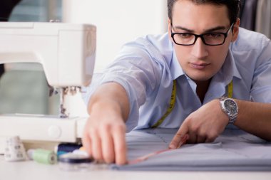 Genç terzi yeni elbiseler üzerinde çalışıyor.
