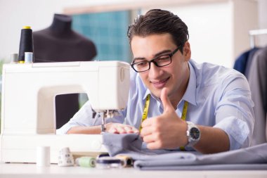 Genç terzi yeni elbiseler üzerinde çalışıyor.