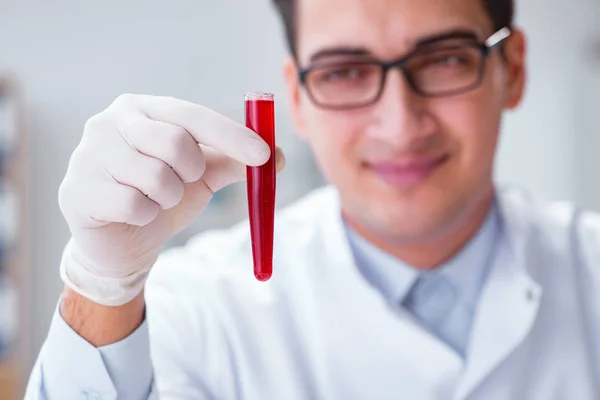 Médico joven en el laboratorio con tubo rojo —  Fotos de Stock