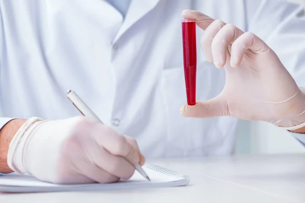 Jovem médico no laboratório com tubo vermelho — Fotografia de Stock