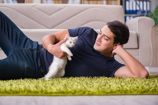 Joven hombre guapo jugando con gatito blanco — Foto de Stock