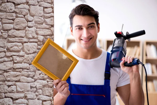 Reparador colocando quadro de imagem na parede — Fotografia de Stock