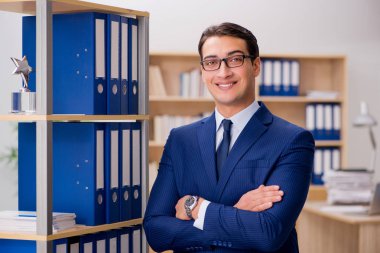 Yakışıklı işadamı raf yanında ayakta