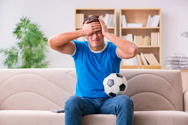 Muž sledující fotbal doma sedící na gauči — Stock fotografie