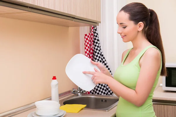 Fiatal feleség mosás edények a konyhában — Stock Fotó