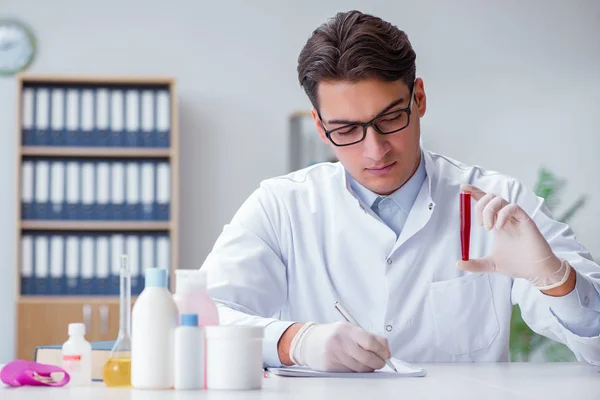 Νεαρός γιατρός στο εργαστήριο με κόκκινο σωλήνα — Φωτογραφία Αρχείου