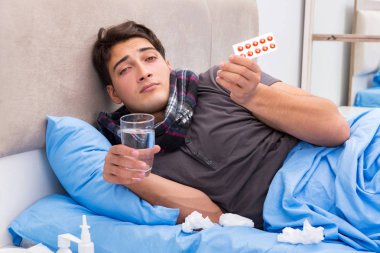 Grip olmuş hasta adam yatakta yatıyor.