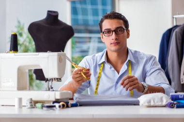 Genç terzi yeni elbiseler üzerinde çalışıyor.