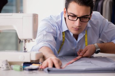 Genç terzi yeni elbiseler üzerinde çalışıyor.