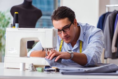 Genç terzi yeni elbiseler üzerinde çalışıyor.