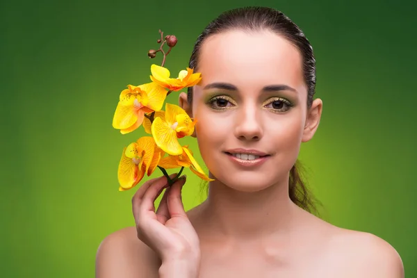 Mulher bonita com flor de orquídea amarela — Fotografia de Stock