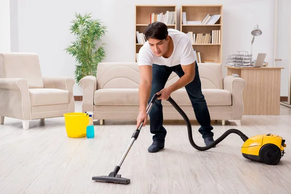 Чоловік прибирає будинок за допомогою пилососа — стокове фото