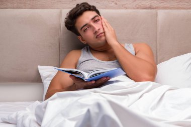 Adam yatakta kitap okumak