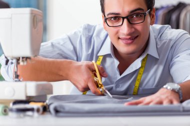 Genç terzi yeni elbiseler üzerinde çalışıyor.