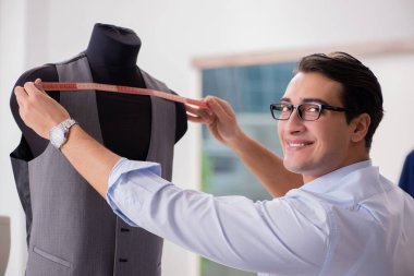 Genç terzi yeni elbiseler üzerinde çalışıyor.