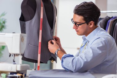 Genç terzi yeni elbiseler üzerinde çalışıyor.