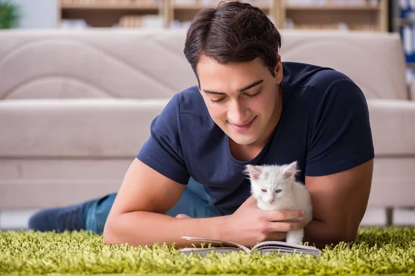 Young handsome man playing with white kitten