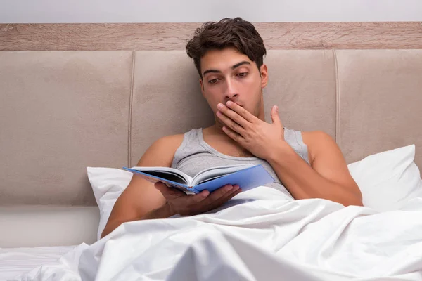 Чоловік читає книгу в ліжку — стокове фото
