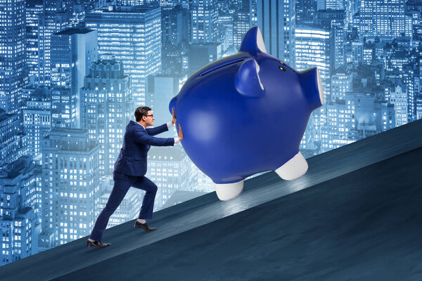 Man pushing piggybank uphill in business concept