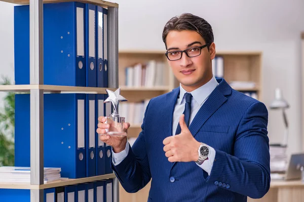 Dosyalarla rafın yanında duran genç adam.