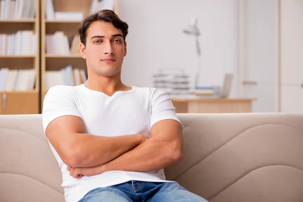 Jovem relaxante sentado no sofá sofá — Fotografia de Stock