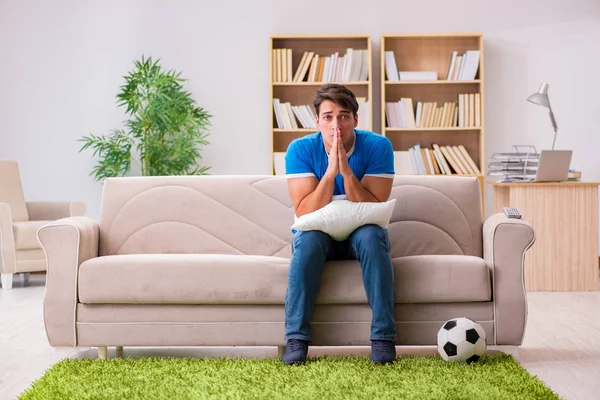 Homem assistindo futebol em casa sentado no sofá — Fotografia de Stock