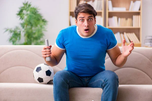 Hombre viendo fútbol en casa sentado en el sofá — Foto de Stock