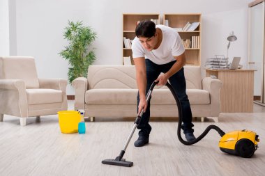 Adam elektrikli süpürgeyle evi temizliyor.