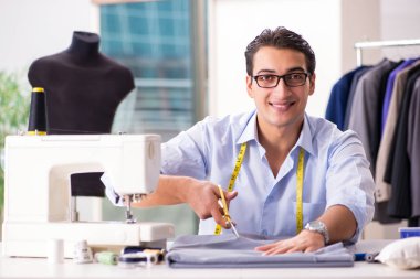 Genç terzi yeni elbiseler üzerinde çalışıyor.