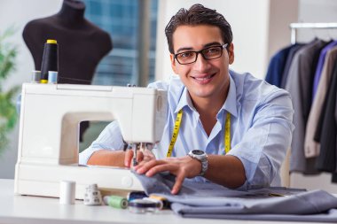 Genç terzi yeni elbiseler üzerinde çalışıyor.