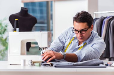 Genç terzi yeni elbiseler üzerinde çalışıyor.