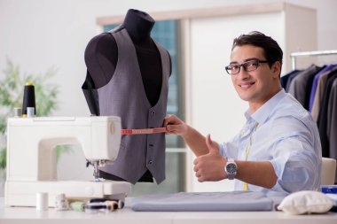 Genç terzi yeni elbiseler üzerinde çalışıyor.