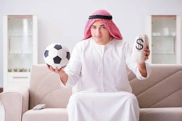 若いですarab男見サッカー座っています上のソファ — ストック写真