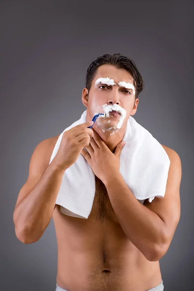 Handsome man shaving against dark background — Stock Photo, Image