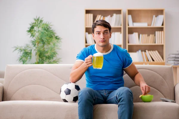 Мужчина смотрит футбол дома, сидя на диване — стоковое фото