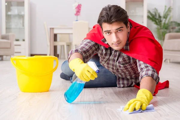 Super herói marido limpeza chão em casa — Fotografia de Stock