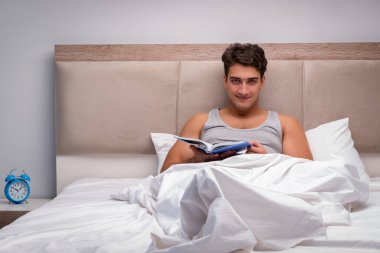 Adam yatakta kitap okumak