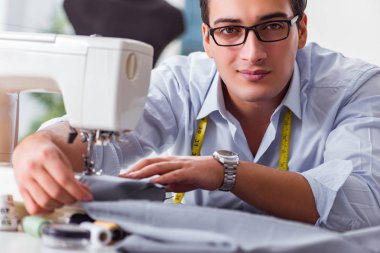 Genç terzi yeni elbiseler üzerinde çalışıyor.