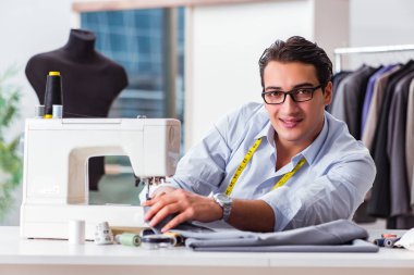 Genç terzi yeni elbiseler üzerinde çalışıyor.