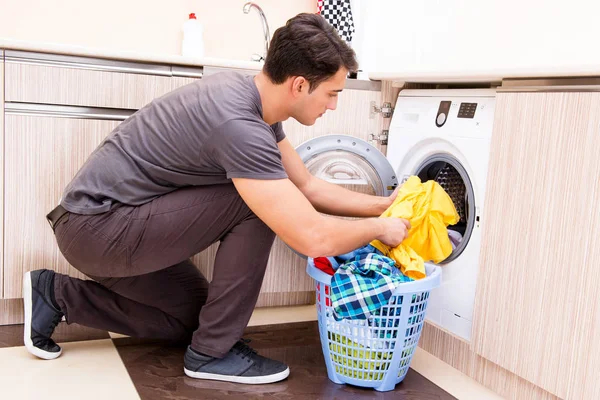 Nuori aviomies mies pesee pyykkiä kotona — kuvapankkivalokuva