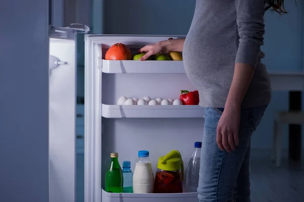 冷蔵庫の近くの妊婦は夜に食べ物や軽食を探しています — ストック写真