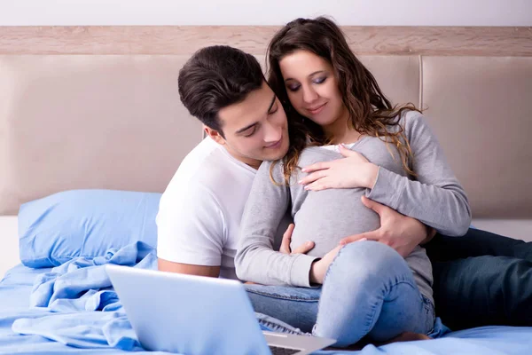 Família jovem com esposa grávida esperando bebê na cama — Fotografia de Stock
