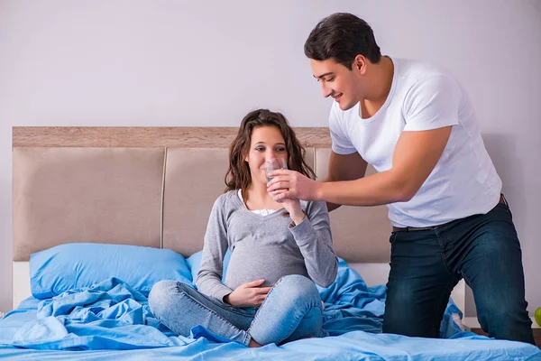 Hamile eşi olan genç bir aile yatakta bebek bekliyor. — Stok fotoğraf