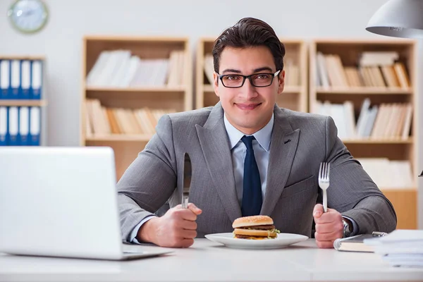 Hambriento empresario divertido comer sándwich de comida chatarra — Foto de Stock